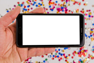 mobile phone with white screen on festive background in hand