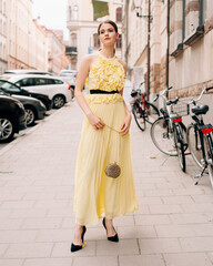Street fashion. Beautiful young model lady walking on city road. Fashionable feminine look. Long...
