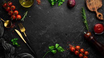Vegetables, spices and herbs on a black stone background. Kitchen background. Top view. Free space...
