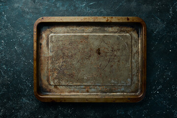 Old metal kitchen tray on a black stone background. Retro tableware. Free space for text.
