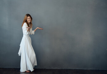 Fototapeta na wymiar Woman in white dress glamor dance gray background