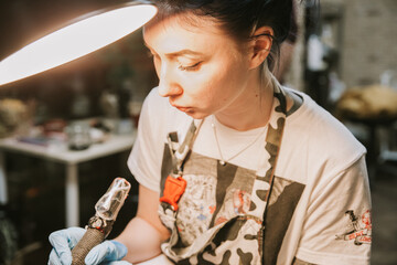 Beautiful creative master is working on new peace of big leg tattoo for customer.