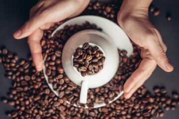inverted white cup on a saucer and coffee beans on a gray table close-ups top view