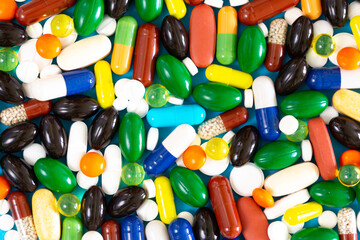 Various medicinal pills and capsules for health, dietary supplements and vitamins for heart health and antiviral agents isolated on blue background. Farm drugs.
