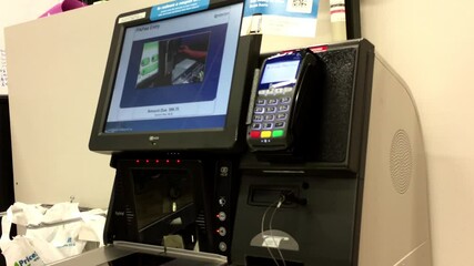 Close up of man tapping Tangerine credit card for paying foods at self-checkout counter inside Price Smart foods store