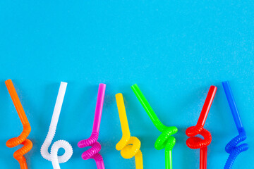 Plastic tubules for drinks on a blue background. Children's party with cocktails. The concept of environmental pollution by plastic, ecology.