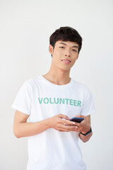 Fototapeta premium Portrait of positive young handsome man joining volunteer organization via application on smartphone