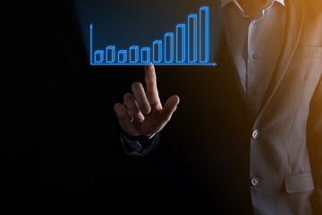 Business man holding holographic graphs and stock market statistics gain profits. Concept of growth planning and business strategy. Display of good economy form digital screen.