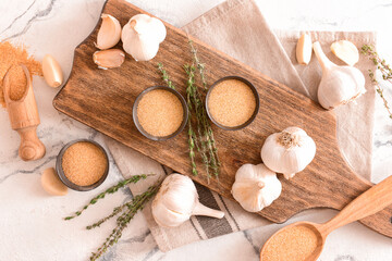 Fototapeta na wymiar Bowls with aromatic powdered garlic on light background
