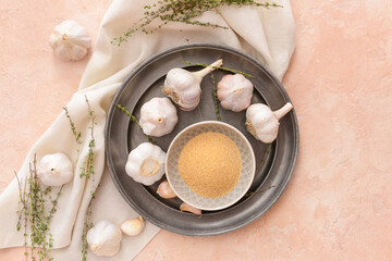 Bowl with aromatic powdered garlic on color background