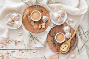 Bowls with aromatic powdered garlic on light wooden background