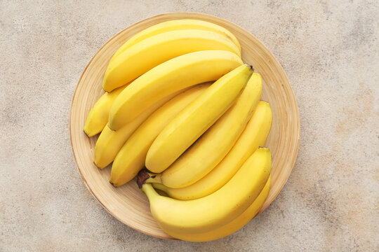 Plate with ripe bananas on light background