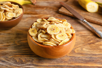 Bowl of crispy banana chips on wooden table