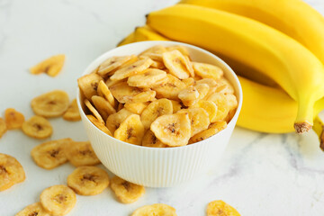 Fresh bananas and crispy chips on light background
