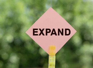 EXPAND - text on pink note paper on green background.
