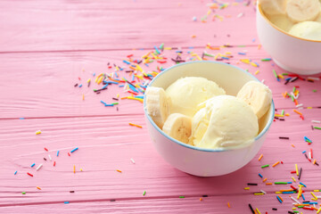 Bowl with tasty banana ice-cream on color wooden background