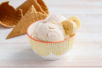 Bowl with tasty banana ice-cream on light wooden background