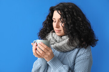 Sick young woman with hot tea on color background