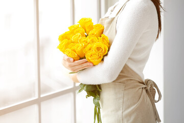 Female florist with beautiful yellow roses in room