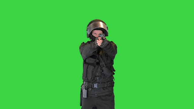 Police unit wearing a bulletproof vest and helmet aiming with a gun on a Green Screen, Chroma Key.