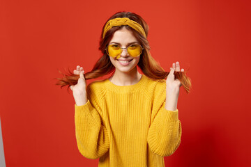 pretty woman in yellow sweater holding hair emotions cropped view red background