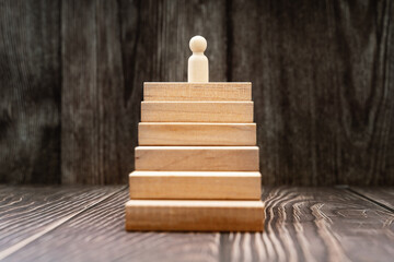 Fototapeta na wymiar Reaching The Top. Wood Figurine on Top of Stairs. Business and Personal Growth Concept.