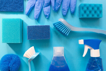 Blue monochrome flay lay of cleaning tool set. Brushes, spray, bottles, sponges. - obrazy, fototapety, plakaty