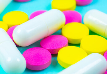 Colored pills and tablets on green background. Close up. Medical treatment concept.