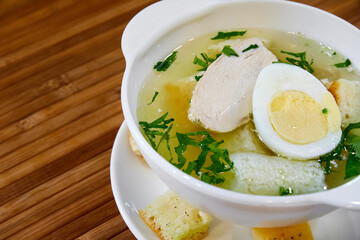 Broth with chicken fillet, egg, croutons and herbs. Close-up, selective focus