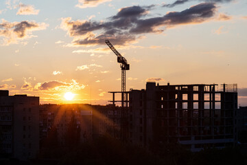 Construction of a new high-rise building among the city on a background of sunset