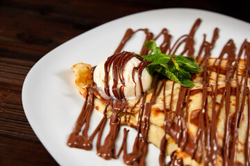 Pancake with a scoop of ice cream and chocolate. Close-up, selective focus