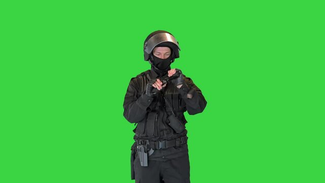Police tactical officer checking his hand gun and folding hands on a Green Screen, Chroma Key.