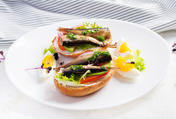 Sandwich - smorrebrod with sprats, avocado, tomatoes, eggs and cream cheese on white plate. Danish cuisine.  Eco friendly concept.