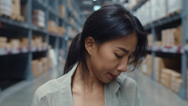 Unhappy young Asia businesswoman manager  looking and feeling confused, scratching her head, expressing doubt stand in retail shopping center. Distribution, Logistics, Packages ready for shipment.