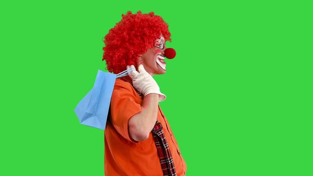 Funny clown on a walk with shopping bags on a Green Screen, Chroma Key.