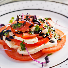 Caprese salad. Mozzarella cheese, tomatoes and basil pesto on plate.  Eco friendly concept.