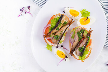 Sandwich - smorrebrod with sprats, avocado, tomatoes, eggs and cream cheese on white plate. Danish cuisine. Top view, overhead. Eco friendly concept.