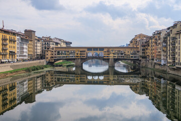 Obraz premium A snapshot with the Ponte Vecchio in the background with its reflection projected on the Arrno river, Firenze, Italy 