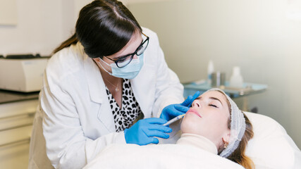 A Woman getting an injection on her lips and face by a doctor. Beauty anti aging treatment at a clinic