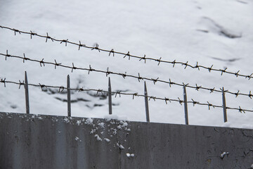 Barbed wire on the fence against light background in the winter  cloudy day