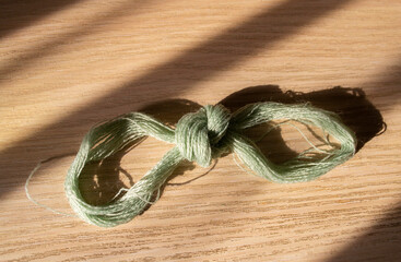 a skein of thread and a shadow falling from it lies on the table
