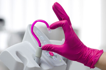 Saliva ejector and a hand in a disposable glove symbolize love in dentistry.Hand in a pink...