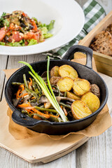 Baked potatoes in a cast iron skillet with onions