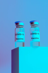 Vial of Covid-19 vaccine  on blue ,purple  fashion  light  background  . Vertical.