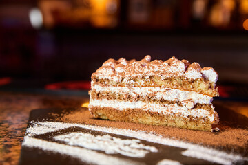 Slice of self-made italian tiramisu dessert served on a plate. Close-up, selective focus