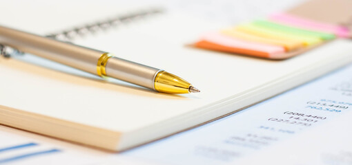 Fototapeta premium Close up of golden pen on notepad background