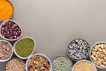 Different types of legumes in bowls, green and yellow peas, chickpeas and peanuts, colored beans and lentils, mung beans and beans, top view