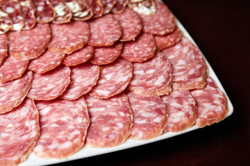Sausage slices on white plate and black background. Close-up