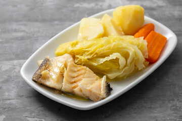 boiled cod fish with boiled vegetables and egg on white dish
