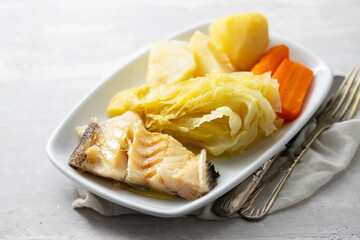 boiled cod fish with boiled vegetables and egg on white dish